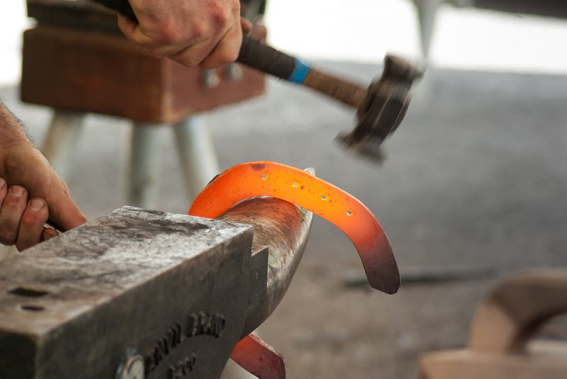 Forger hitting metal on anvil