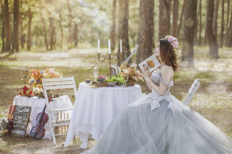 The bride is sitting at a decorated table in the forest