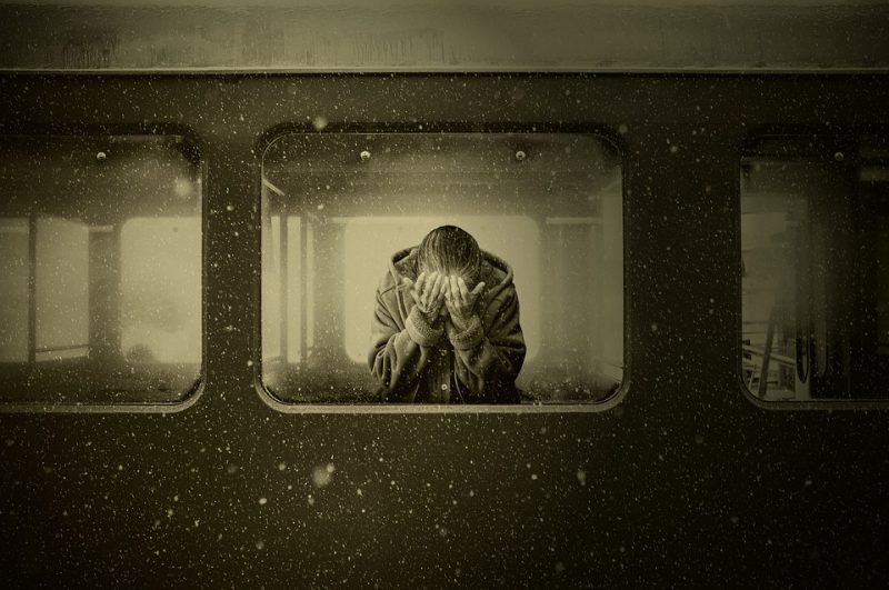 A person sits in a train and mourns