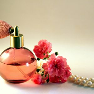 Perfume with flower and necklace next to it