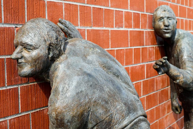 Statue in the form of a man eavesdropping through the wall