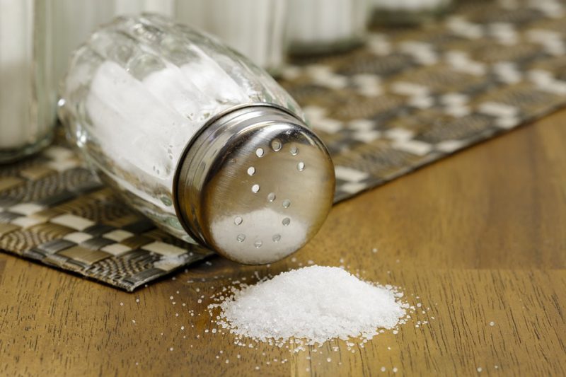 A fallen salt shaker with a little salt