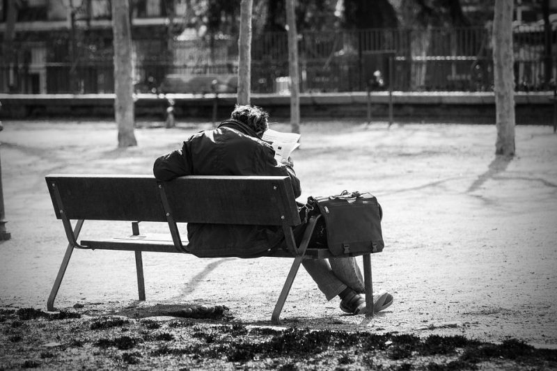 A man sits on a bench and reads