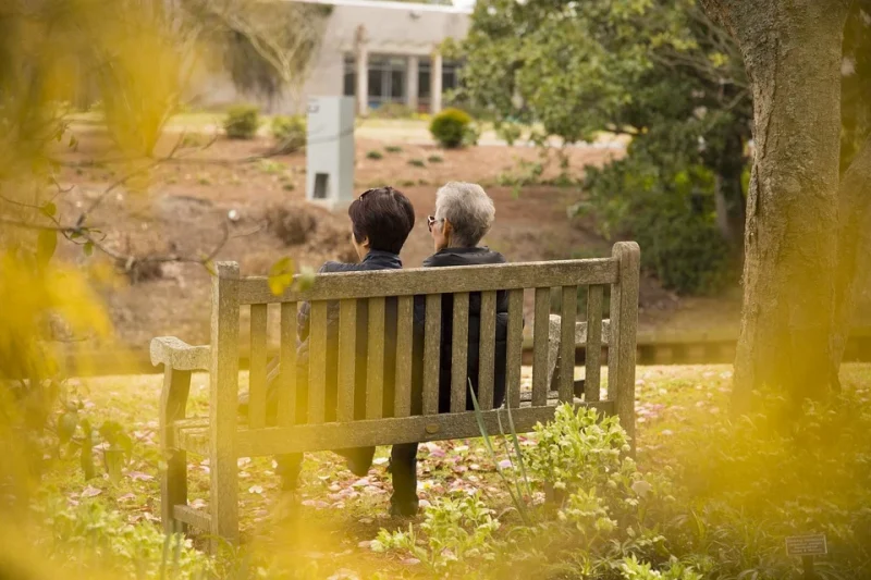 Two women are sitting on a bench and talking