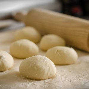 Dough balls with a rolling pin in the background