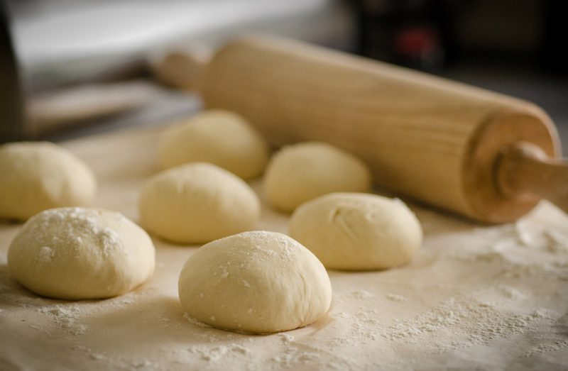 Dough balls with a rolling pin in the background