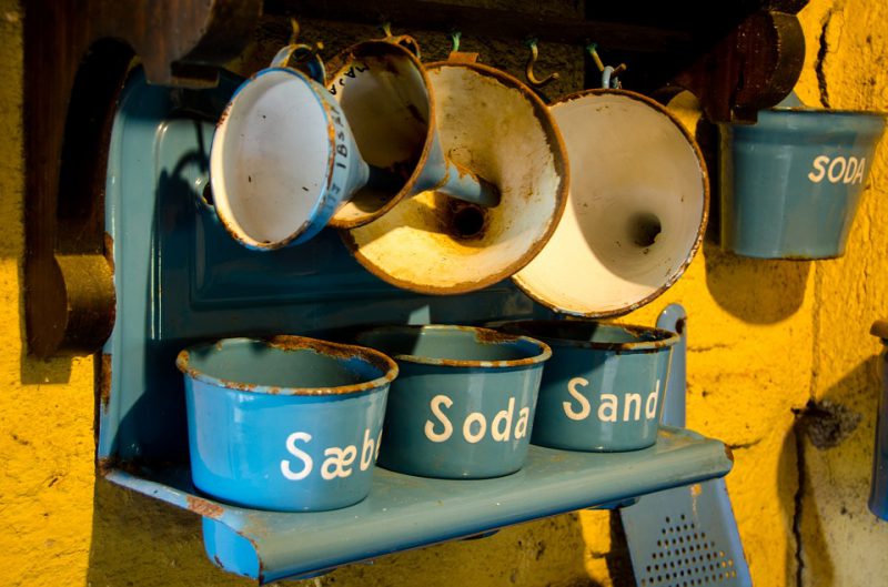 Old rusty blue pots on a shelf with funnels hanging above them