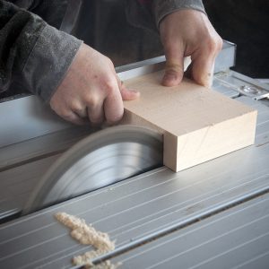 A carpenter cuts a piece of wood on a machine
