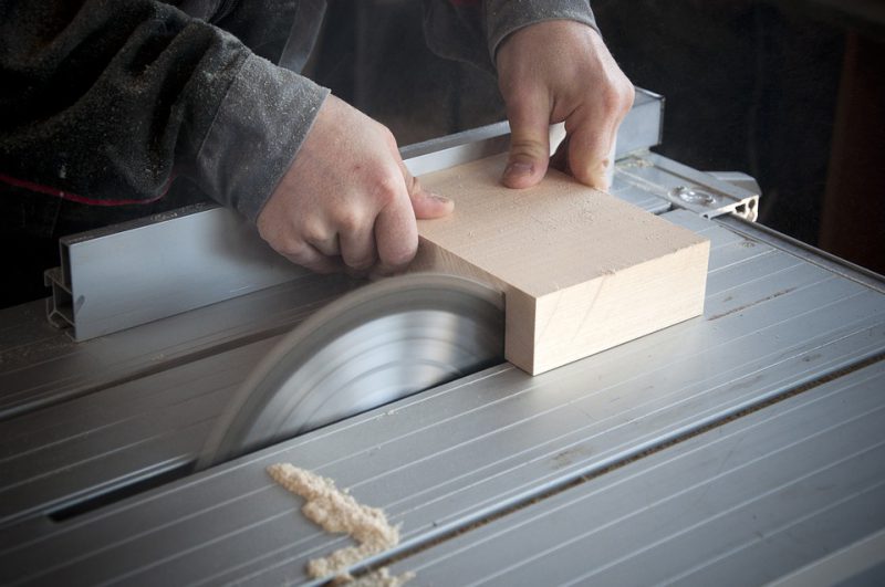 A carpenter cuts a piece of wood on a machine