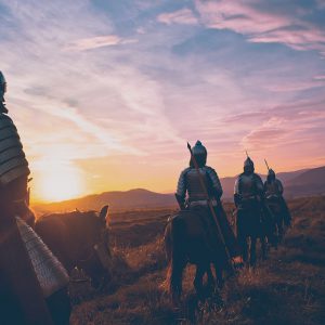 Medieval knights travel on horseback at sunset