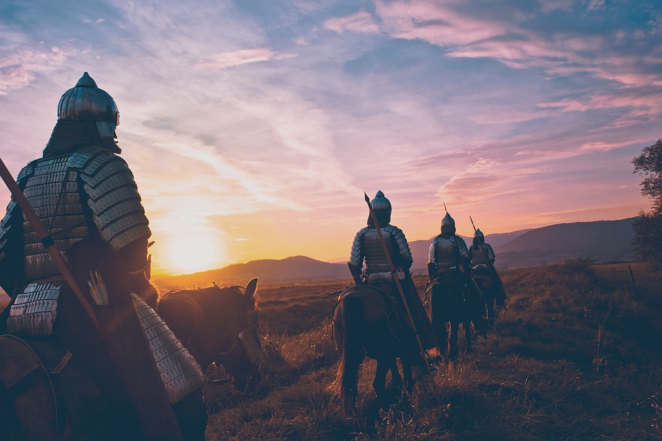 Medieval knights travel on horseback at sunset