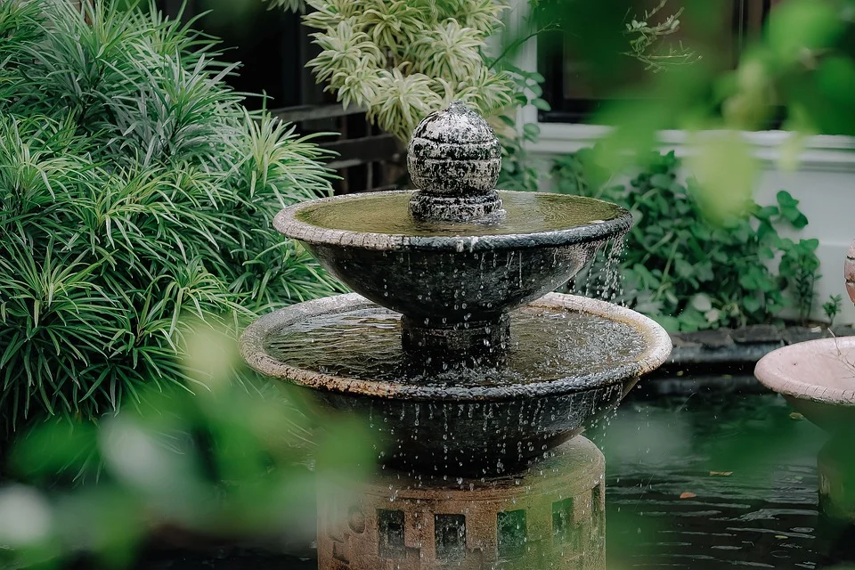 A garden fountain with various greenery around it