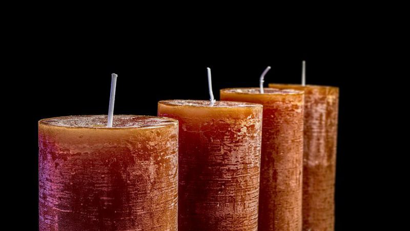 Four candles lined up in a row with a black background