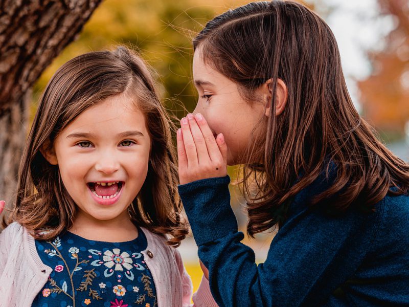 A little girl whispers something to another little girl