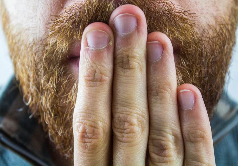 Man's mouth covered with fingers