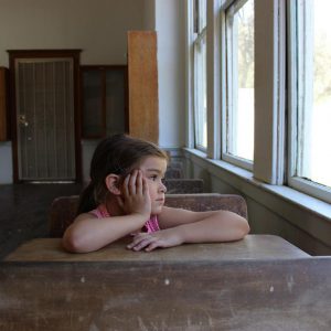 The girl is sitting in the school desk