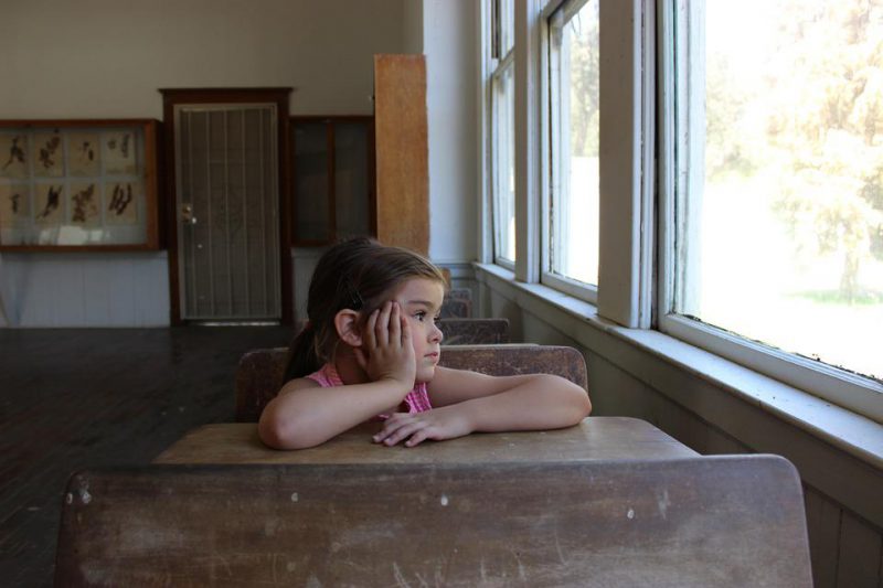 The girl is sitting in the school desk