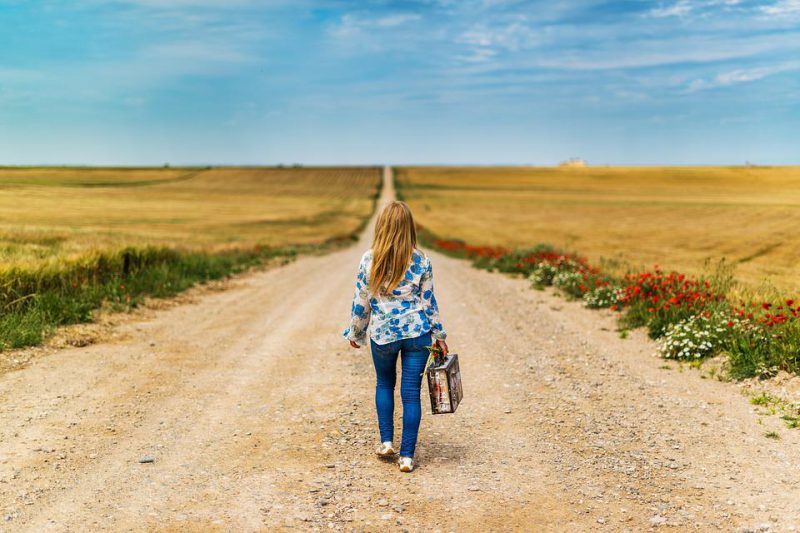 A woman walks on a field road