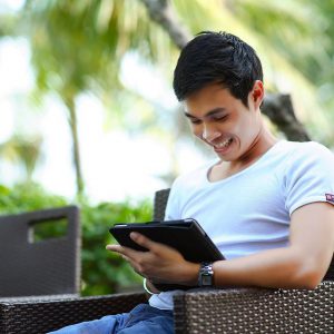 A man is holding a tablet and looking something on it