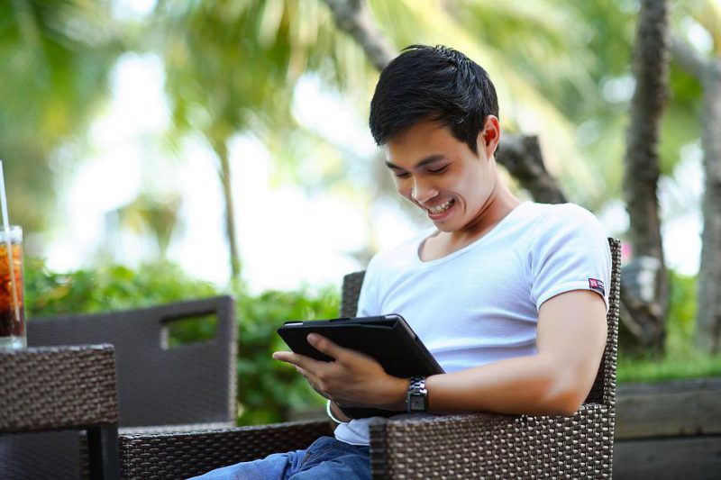 A man is holding a tablet and looking something on it