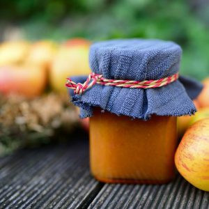 Jar of jam with apples in the back
