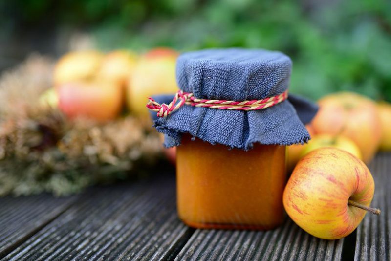 Jar of jam with apples in the back