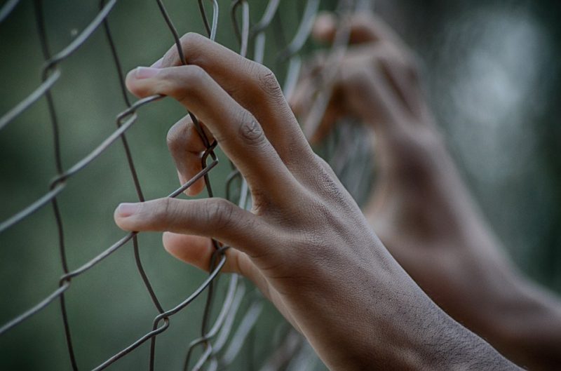 Hands holding to the fence